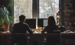 a couple of people sitting at a desk with computers