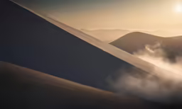 a sun rising behind a cloud covered mountain