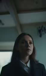 a woman standing in a dark room staring into the camera
