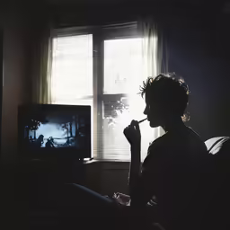 a young man looks out a window and holds a toothbrush
