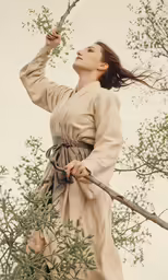 a woman in a long dress holding a branch