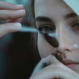 a woman is wearing makeup and holding her hand to her cheek