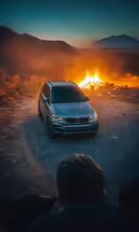 a car in a desert with fire in the background