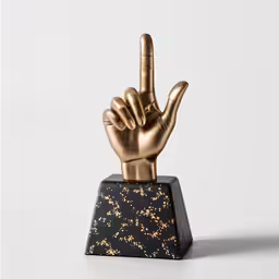 a metal statue depicting the middle finger on top of a black marble base