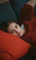 a girl looking off into the distance, laying down on a couch