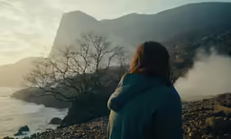 a person staring out at the water at dusk