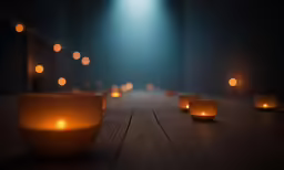 lit candles sit on a wooden table in the dark