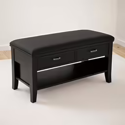 a black bench sits in front of a white wall