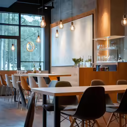 a restaurant with tables and hanging lights in the background