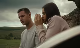 two people who are standing next to a vehicle