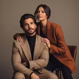 a woman posing for a picture with a man in a brown suit