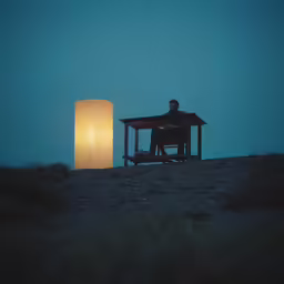 a man sitting at a table and reading by an electric lamp