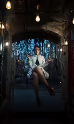 a woman sitting on a swing under some lights