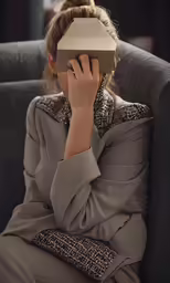 a woman sitting in a chair wearing a hat while looking at something
