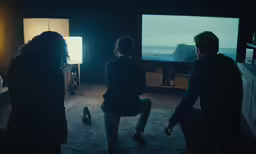 three people watching something in a darkened living room