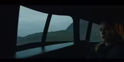 a woman driving in the dark, with mountains in the background