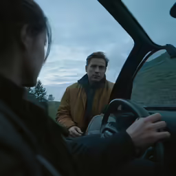man with driver seat in vehicle staring at other person