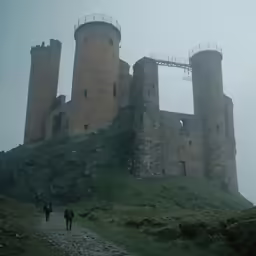some people are walking on a trail near an old castle