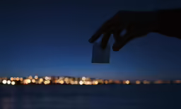 a person holding up a piece of paper near water