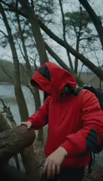 a man stands near some trees with a backpack