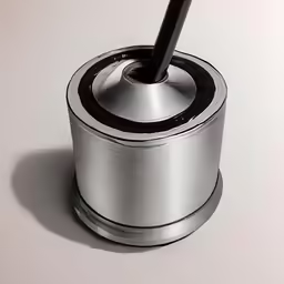 a silver tin has a round black pen in it
