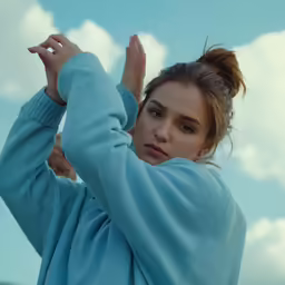 a young woman wearing a blue sweater stretching her arms