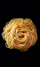 close up of spaghetti noodles against a black background