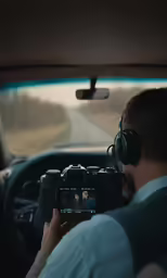 a person on a car taking a photo with a digital camera