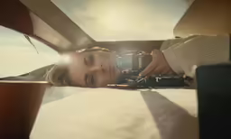a woman laying on top of a bed next to a camera