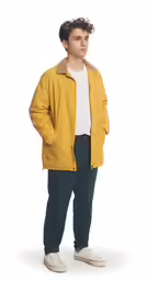 a man standing with his arms in his pockets and wearing an overcoat