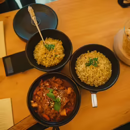 a table with three bowls and plates of food