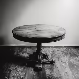 an old round wooden table sits on a wooden floor