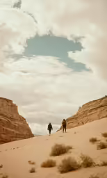 people are walking across the sand near some mountains