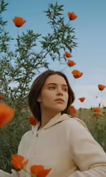 a girl in a field of orange flowers looks up