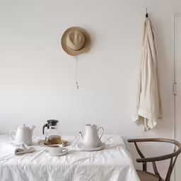 a table with two pitchers, a teapot and two cups on it
