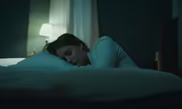 a woman lying on the bed sleeping with the light on