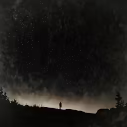 a lone man standing on a hill looking at stars