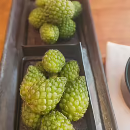 several metal trays with fruits in it on a table