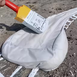 someone holding a white bottle over a gray bag