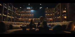 a man and woman sitting on a couch in a theatre