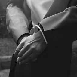 a person wearing a white shirt and black vest holding a wristband