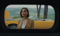 a woman standing in front of a yellow car