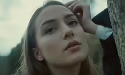 a woman leaning against a tree with her eyes closed