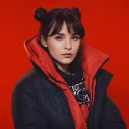 a woman with short hair is wearing a black jacket and a red scarf