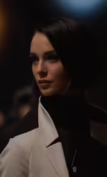 a model in a black top with a white blazer and a silver necklace