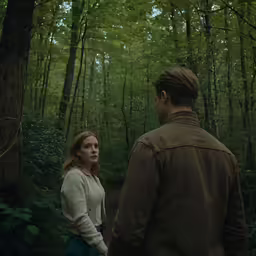 a man and woman standing in the middle of a forest