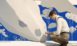 the man crouched down on the ground touching a painting