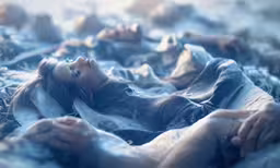 a woman laying down in bed covered with blankets
