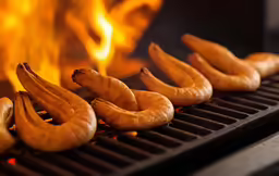 several hot dogs sit on top of a grill