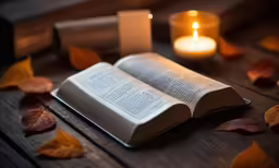 a book sitting on top of a wooden table next to a candle